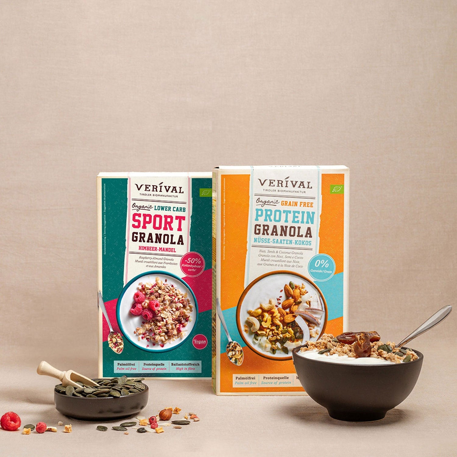 Two boxes of Veríval granola, one sports granola and one protein granola, presented with a bowl of granola, seeds and berries on a beige background.