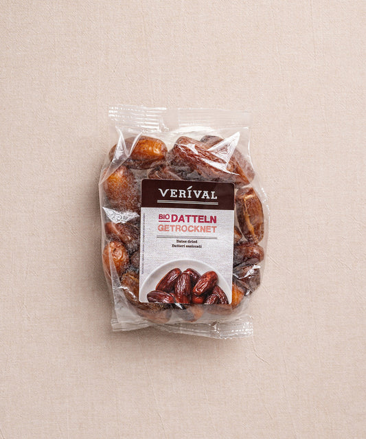 Auf einem beigen Untergrund liegt eine Packung getrockneter Datteln von Verival Bio, die auf Deutsch und Englisch beschriftet ist und den Verzicht auf Konservierungsstoffe unterstreicht.