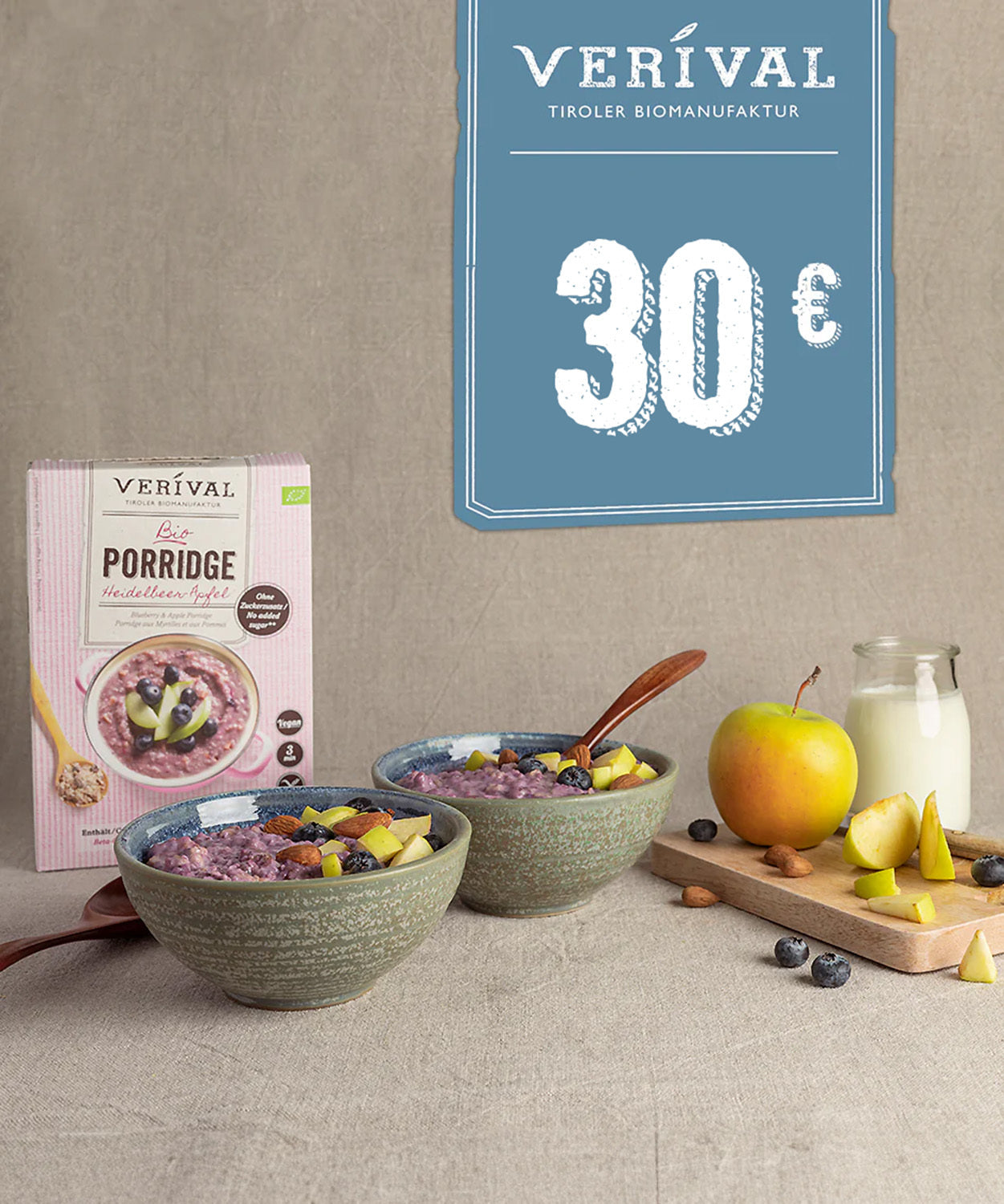 Zwei Schalen Verival Bio Brei mit Obst, einem Apfel, Blaubeeren und Milch auf dem Tisch; ein Verival Geschenk-Gutschein (25€, 50€, 100€) der Verival Bio GmbH bietet pure Frühstücksfreude für Ihren Morgen.